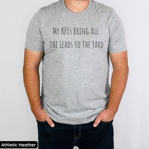 Pu&ograve; includere: Una t-shirt color grigio melange con la scritta "My KPI's Bring All The Leads To The Yard" stampata sul davanti.