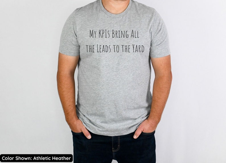 Pu&ograve; includere: Una t-shirt color grigio melange con la scritta "My KPI's Bring All The Leads To The Yard" stampata sul davanti.