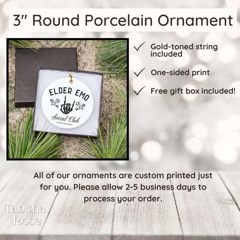 May include: A 3-inch round porcelain ornament with the text "ELDER EMO Social Club" and a skeleton hand illustration. The ornament includes a gold-toned string and a free gift box. The ornament is white with black text and graphics.