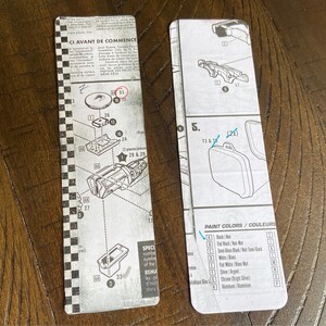 May include: A black and white instruction sheet for assembling a model kit. The sheet includes diagrams and numbers for each piece, as well as a list of paint colors. The text on the sheet reads "CI AVANT DE COMMENCE" and "PAINT COLORS/COULEURS".