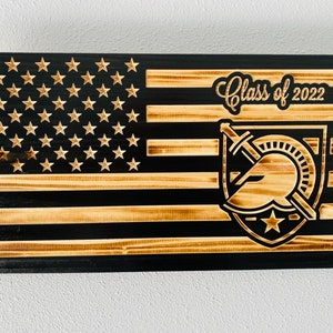 May include: A wooden American flag with a black background and a gold Spartan helmet logo. The text "Class of 2022" is written above the logo.