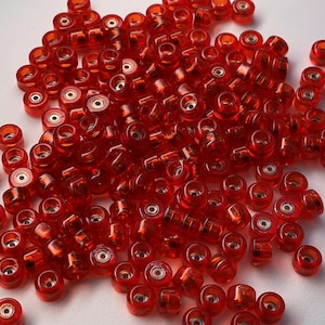 May include: A large pile of red plastic skateboard wheels. The wheels are small and have a metal bearing in the center.