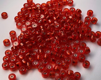 May include: A large pile of red plastic skateboard wheels. The wheels are small and have a metal bearing in the center.
