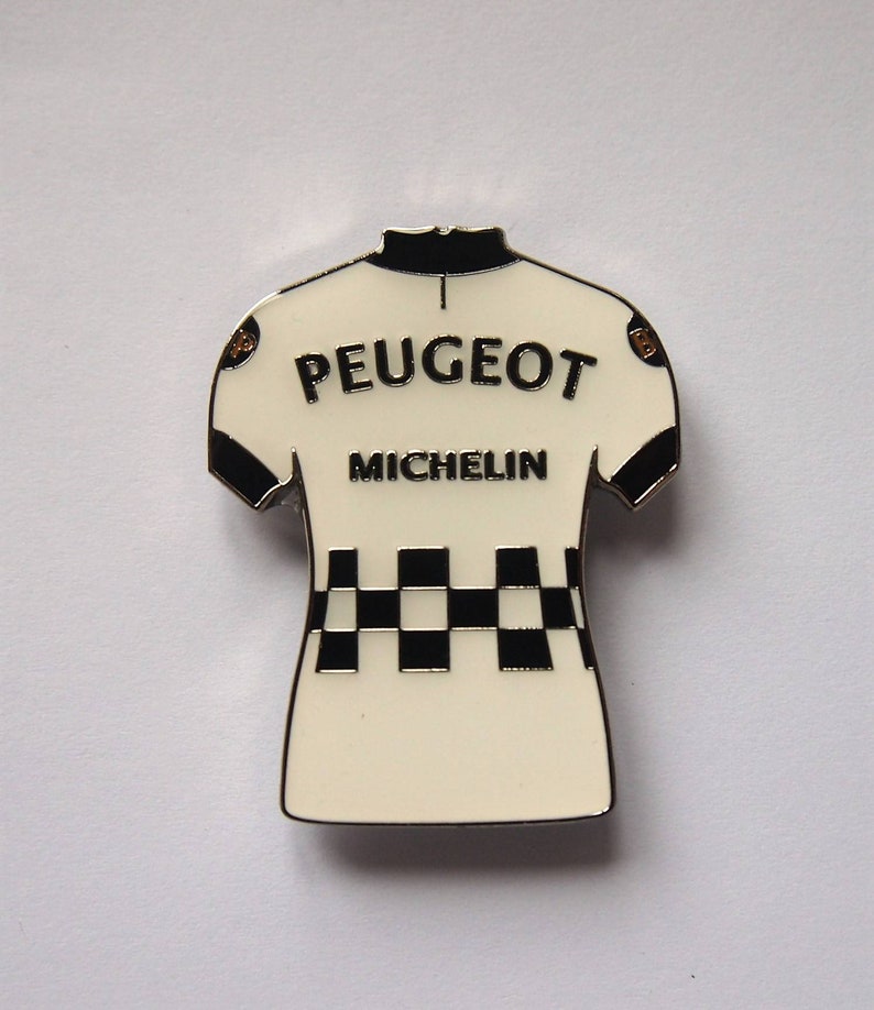 K&ouml;nnte beinhalten: Wei&szlig;er Radsporttrikot-Pin mit schwarz-wei&szlig;em Karomuster, 'PEUGEOT' und 'MICHELIN' Schriftzug.