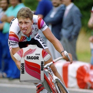 May include: A white cycling jersey with red and pink stripes and the text "MBK FAGOR" on the front. The jersey has the word "FAGOR" on both sleeves.