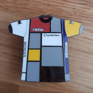 May include: A black and white cycling jersey with a geometric design. The jersey has red, yellow, and blue accents. The text "radar" and "La Vie Claire" are printed on the jersey. The text "WONDER" is printed on the side of the jersey.