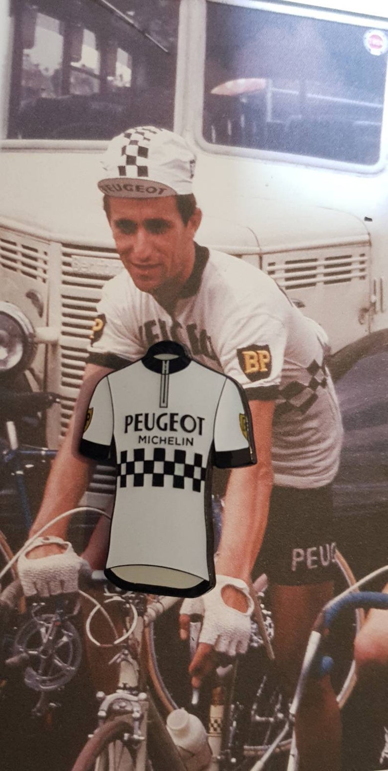 K&ouml;nnte beinhalten: Ein wei&szlig;es Radtrikot mit einem schwarzen Rei&szlig;verschluss und einem schwarz-wei&szlig;en Karomuster. Das Trikot tr&auml;gt den Aufdruck "PEUGEOT MICHELIN" auf der Vorderseite.