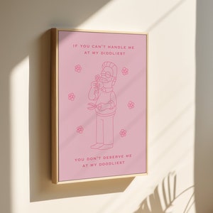 May include: A pink framed print with a cartoon illustration of a man holding a flower and a pair of scissors. The text reads "If you can't handle me at my diddliest, you don't deserve me at my doodliest."