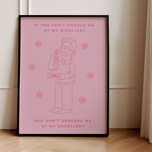 May include: A pink framed poster with a cartoon illustration of a man with a mustache and glasses holding a flower. The text on the poster reads "If you can't handle me at my diddliest, you don't deserve me at my doodliest."