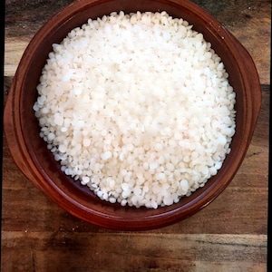 May include: A brown ceramic bowl filled with white wax beads.
