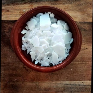 Può includere: Primo piano di una ciotola di ceramica marrone piena di fiocchi di cera bianca.