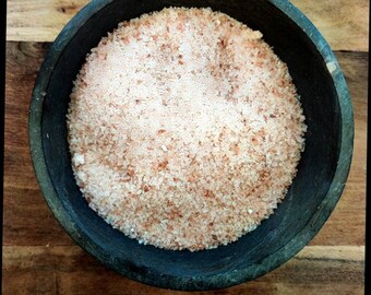 May include: A close-up of a black bowl filled with pink Himalayan salt crystals.