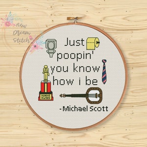 May include: A white embroidery hoop with a cross-stitch design featuring the quote "Just poopin' you know how I be - Michael Scott". The design includes a toilet, toilet paper, a tie, a banjo, and a Dundie Award.
