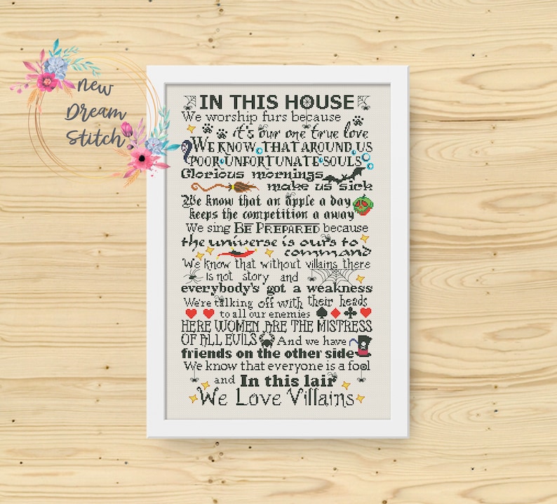 Pu&ograve; includere: Un'opera d'arte incorniciata, ricamata a punto croce, con il testo "IN THIS HOUSE We Love Villains". Il pezzo con cornice bianca presenta varie frasi e illustrazioni, tra cui impronte di zampe, un teschio e semi di carte da gioco. L'opera &egrave; su uno sfondo di legno.