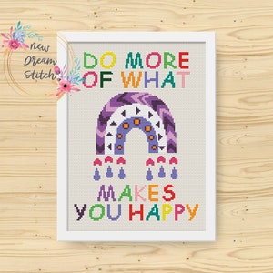 Könnte beinhalten: Ein gerahmtes Kreuzstich-Kunstwerk mit dem Text "DO MORE OF WHAT MAKES YOU HAPPY". Das Design zeigt einen lila-orangenen Regenbogen mit Regentropfen. Das Kunstwerk befindet sich in einem weißen Rahmen und liegt auf einer Holzoberfläche.