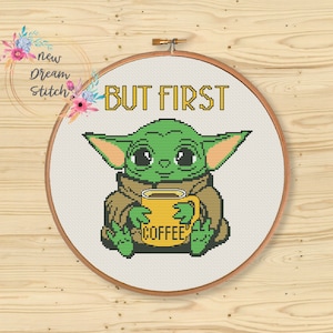 May include: Cross stitch pattern featuring a green alien character holding a yellow coffee mug with the text "COFFEE" on it. The text "BUT FIRST" is above the character.