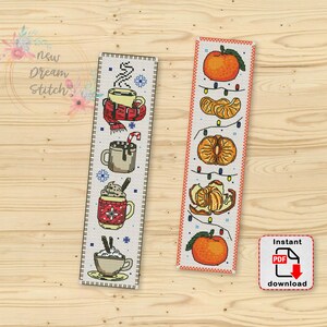 Op de afbeelding: Twee kruissteek-bladwijzerpatronen. Eén met een winterthema met warme chocolademelk, slagroom en snoepstokken. De andere met een citrus thema met sinaasappelen en bladeren. Beide patronen zijn op witte Aida-stof.