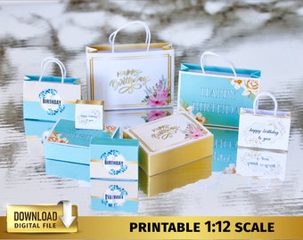 Könnte beinhalten: Druckbare Geburtstagsgeschenkkisten und -taschen im Maßstab 1:12. Die Kisten sind blau mit goldenen Verzierungen und Blumendesigns. Die Taschen sind weiß und blau mit goldenen Verzierungen und Blumendesigns. Der Text auf den Kisten und Taschen lautet "Happy Birthday".