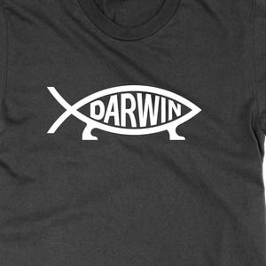 Op de afbeelding: Een antracietgrijs T-shirt met korte mouwen en een witte afbeelding van een vissymbool met poten en de tekst DARWIN in het lichaam van de vis. Het ontwerp is gecentreerd op de borst van het T-shirt, dat een ronde halslijn heeft.