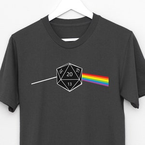 Könnte beinhalten: Ein dunkelgraues T-Shirt mit einer weißen Grafik eines 20-seitigen Würfels, einem Regenbogenprisma und dem Text "16, 20, 13, 21".