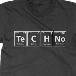 Peut inclure: Un t-shirt gris foncé avec un graphique blanc du tableau périodique des éléments qui épelle le mot "TECHNO". Les éléments sont le tellure (Te), le carbone (C), l'hydrogène (H) et le nobélium (No).
