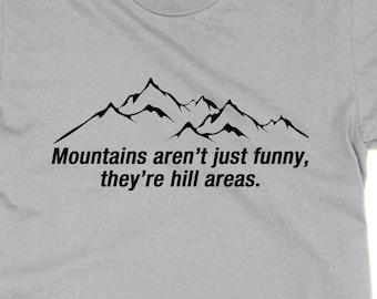Peut inclure: Un t-shirt gris clair avec un motif de chaîne de montagnes noires et le texte "Mountains aren't just funny, they're hill areas."