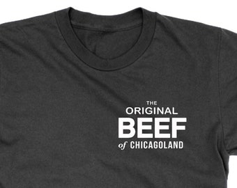 Op de afbeelding: Een donkergrijs T-shirt met witte tekst die "THE ORIGINAL BEEF of CHICAGOLAND" luidt.