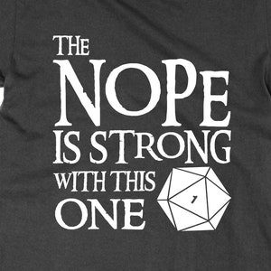 Könnte beinhalten: Ein dunkelgraues T-Shirt mit weißem Text, der "The Nope is Strong with this One" lautet, und einem weißen Bild eines 20-seitigen Würfels mit einer 1.