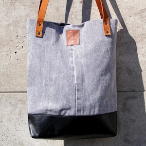 Könnte beinhalten: Eine graue und schwarze Tragetasche mit braunen Ledergriffen und einem Lederpatch mit der Aufschrift "SUGAR".