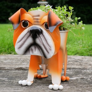 May include: Orange and white metal bulldog planter with green plants growing out of the top.