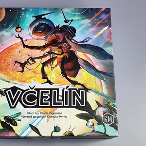K&ouml;nnte beinhalten: Eine farbenfrohe Brettspielbox mit einer Biene, die einen Weltraumhelm tr&auml;gt und ein Werkzeug h&auml;lt. Die Box ist mit "VČELIN" betitelt und enth&auml;lt den Text "N&aacute;vrh hry: Connie Vogelmann" und "V&yacute;tvarn&eacute; zpracov&aacute;n&iacute;: Kwanchai Moriya".