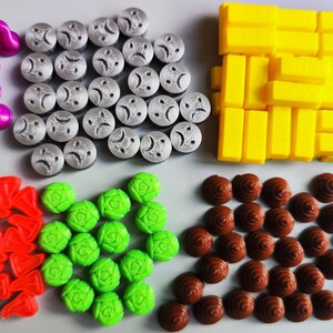 May include: Assortment of colorful plastic game pieces, including purple, red, green, silver, and yellow. The pieces are arranged in five groups on a gray surface.