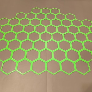 Peut inclure: Un plateau de jeu en forme de nid d'abeilles vert vif avec le mot « START » imprimé en blanc. Le plateau est fait d'un matériau léger et est conçu pour les jeux de société. La grille hexagonale est clairement définie.