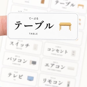 May include: A rectangular white sticker featuring the Japanese characters for table, the hiragana reading, and the English word TABLE in black text, accompanied by a small illustration of a light brown wooden table with four legs.