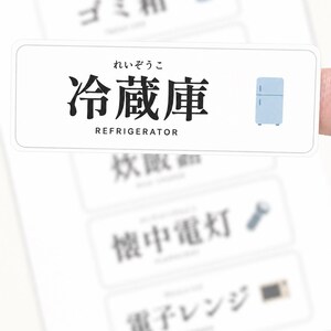 May include: A rectangular white label featuring the Japanese kanji for refrigerator, the hiragana reading, and the English word REFRIGERATOR in black text, accompanied by a small blue refrigerator icon. Other blurred labels are visible in the background.