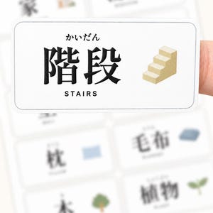 May include: A rectangular white sticker featuring the Japanese kanji for stairs, the hiragana reading kaidan, and the English word STAIRS in black text, accompanied by a small beige isometric illustration of a staircase with four steps.