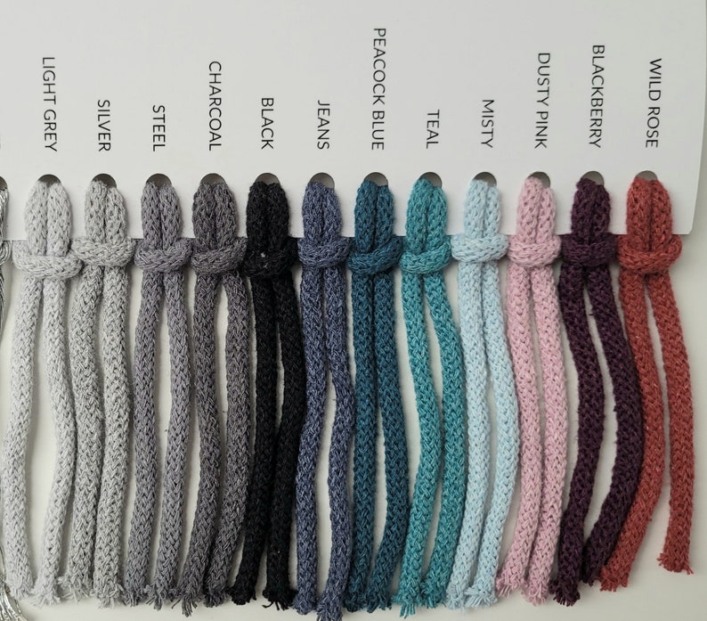 May include: A colour chart of 12 different colours of cotton cord. The colours are: Wild Rose, Blackberry, Dusty Pink, Misty, Teal, Peacock Blue, Jeans, Black, Charcoal, Steel, Silver, and Light Grey.