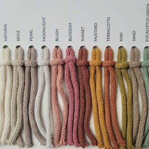 May include: A colour chart of 17 different colours of cotton cord. The colours are: White, Rainbow Dust, Golden Natural, Natural, Beige, Pearl, Moonlight, Blush, Blossom, Sunset, Mustard, Terracotta, Kiwi, Sand, Eucalyptus Green, Laurel, and Avocado.