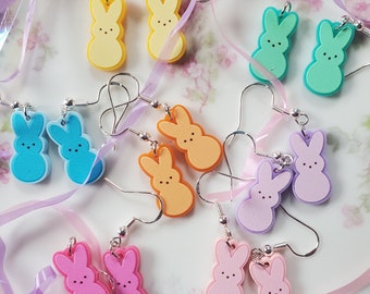 Peut inclure: Assortiment de boucles d'oreilles en forme de lapin de couleur pastel. Les boucles d'oreilles sont en pâte polymère et sont disponibles en jaune, bleu, vert, orange, rose et lavande.