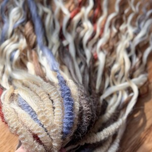 May include: A bundle of multi-colored curly hair extensions. The extensions feature a mix of blonde, brown, red, and blue tones. The hair is tightly curled and appears to be made of synthetic fibers, perfect for creating a voluminous hairstyle.