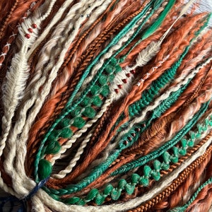 May include: A bundle of synthetic hair extensions in shades of brown, beige, and green. The extensions are braided and have beads woven into them.