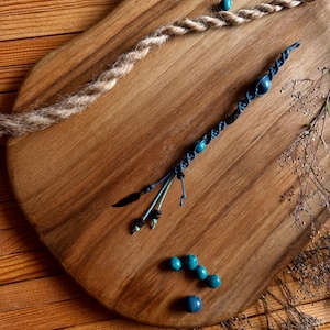 Peut inclure: Un plateau de service en bois présente une collection d'accessoires pour cheveux faits à la main. Un wrap capillaire torsadé brun clair et un wrap capillaire macramé bleu avec des perles bleues sont présentés. Plusieurs perles bleues sont éparpillées sur le plateau.