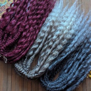 May include: Three strands of curly yarn hair for dolls. The strands are burgundy, light gray with brown highlights, and dark gray with light gray highlights.