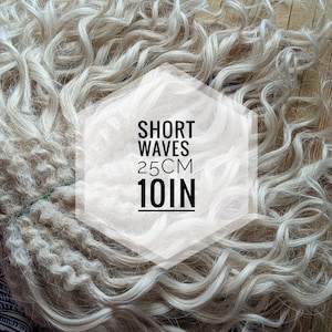May include: A bundle of blonde short wave human hair extensions. The hair is 10 inches long and is arranged in a loose pile. The text "SHORT WAVES 25CM 10IN" is printed on a white hexagon.