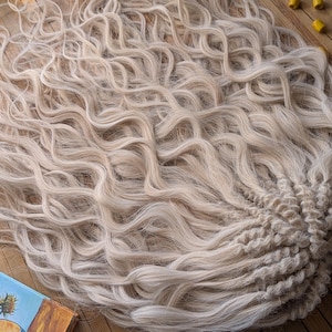 May include: A long, wavy, light blonde hair extension with a braided base. The hair is very light blonde with a slight white tint.