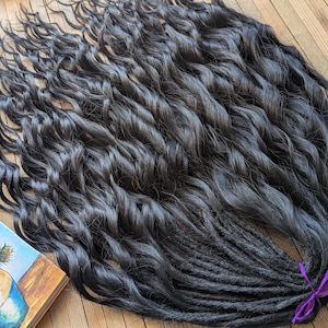 May include: A set of long, black dreadlocks with a wavy texture. The dreadlocks are tied together with a purple ribbon.