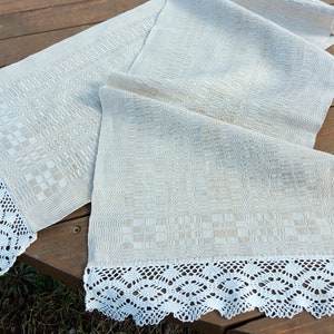May include: A white linen table runner with a checkered pattern and a white crocheted lace trim.