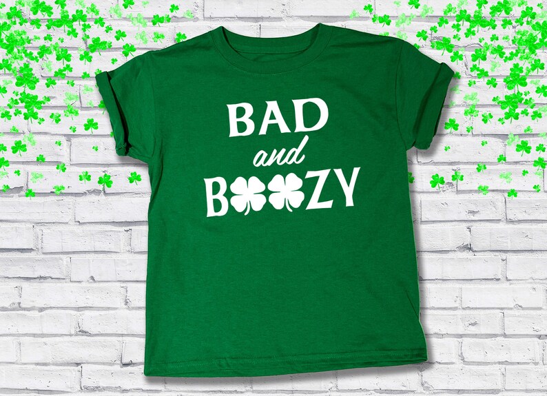 May include: Green t-shirt with white text that reads "BAD and BOOZY" with four shamrocks.