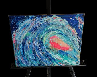 Puede incluir: Pintura abstracta de una ola rompiendo en el océano. La obra presenta una composición dinámica con remolinos de azules, verdes y blanco, acentuados por un toque de rosa. La pintura se exhibe sobre un caballete negro, sobre un fondo negro.
