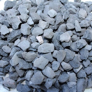 May include: A pile of small, gray, irregularly shaped rocks. The rocks are about the size of a quarter.